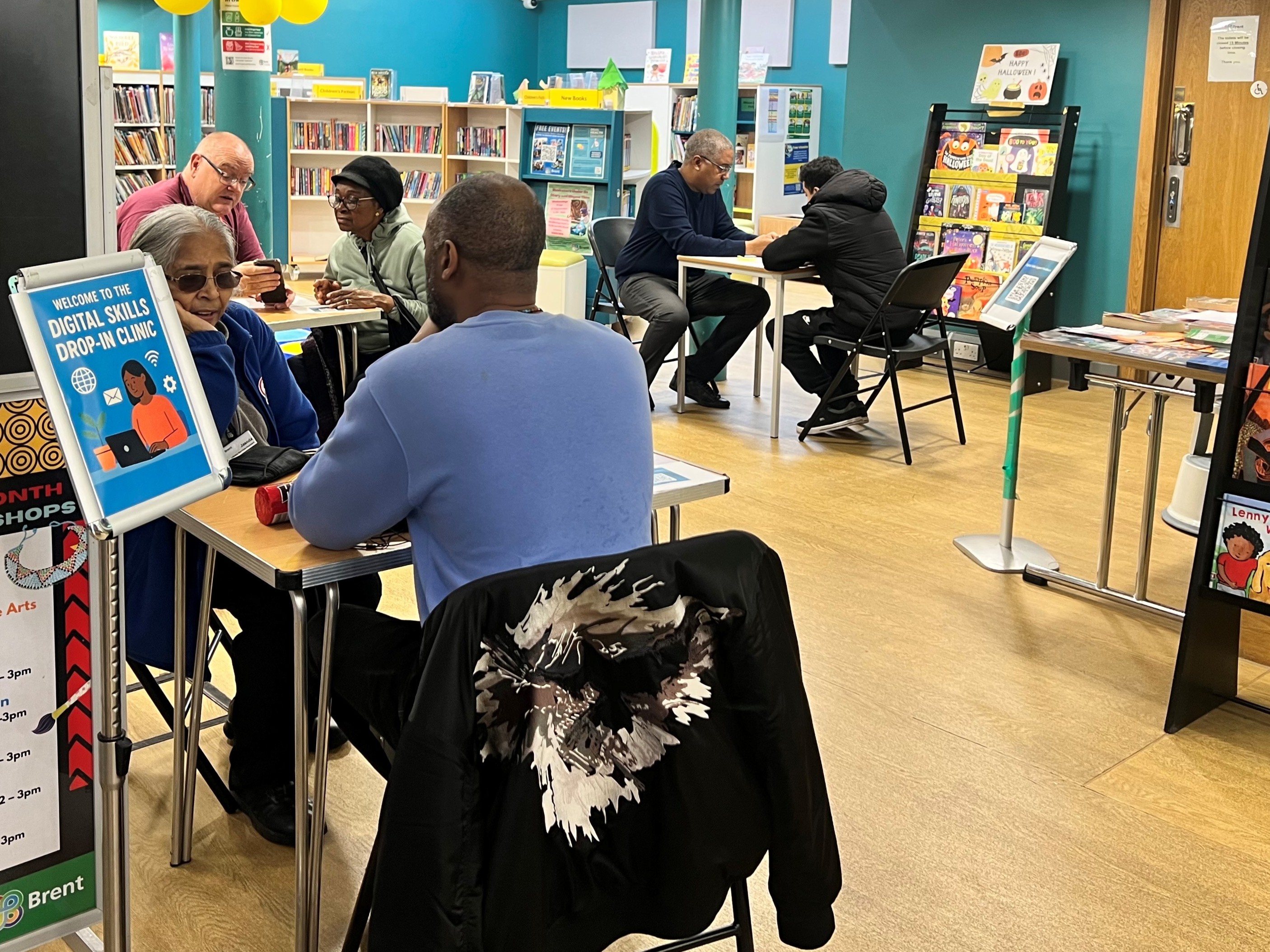 Residents sitting at desks in a library talking to people about technology