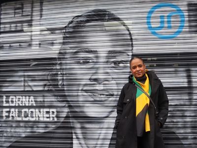 Photograph of a woman standing in front of a mural of Lorna Falconer