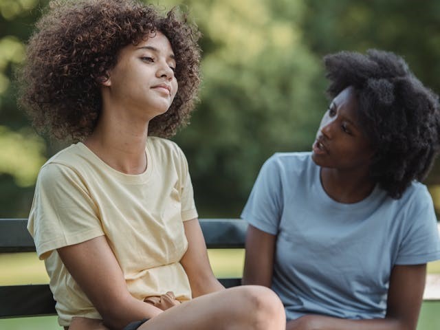 mother and teen talking on park bench