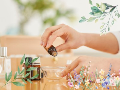 hands drop oil into a bowl with flowers and leaves