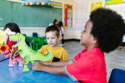 An image of two boys playing with a dinosaur