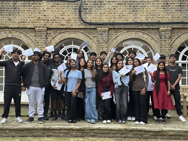 Group of boys and girls holding pieces of paper in the air with their exam results