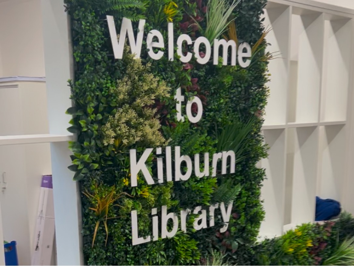 Sign on living wall reads 'welcome to kilburn library'  in white 