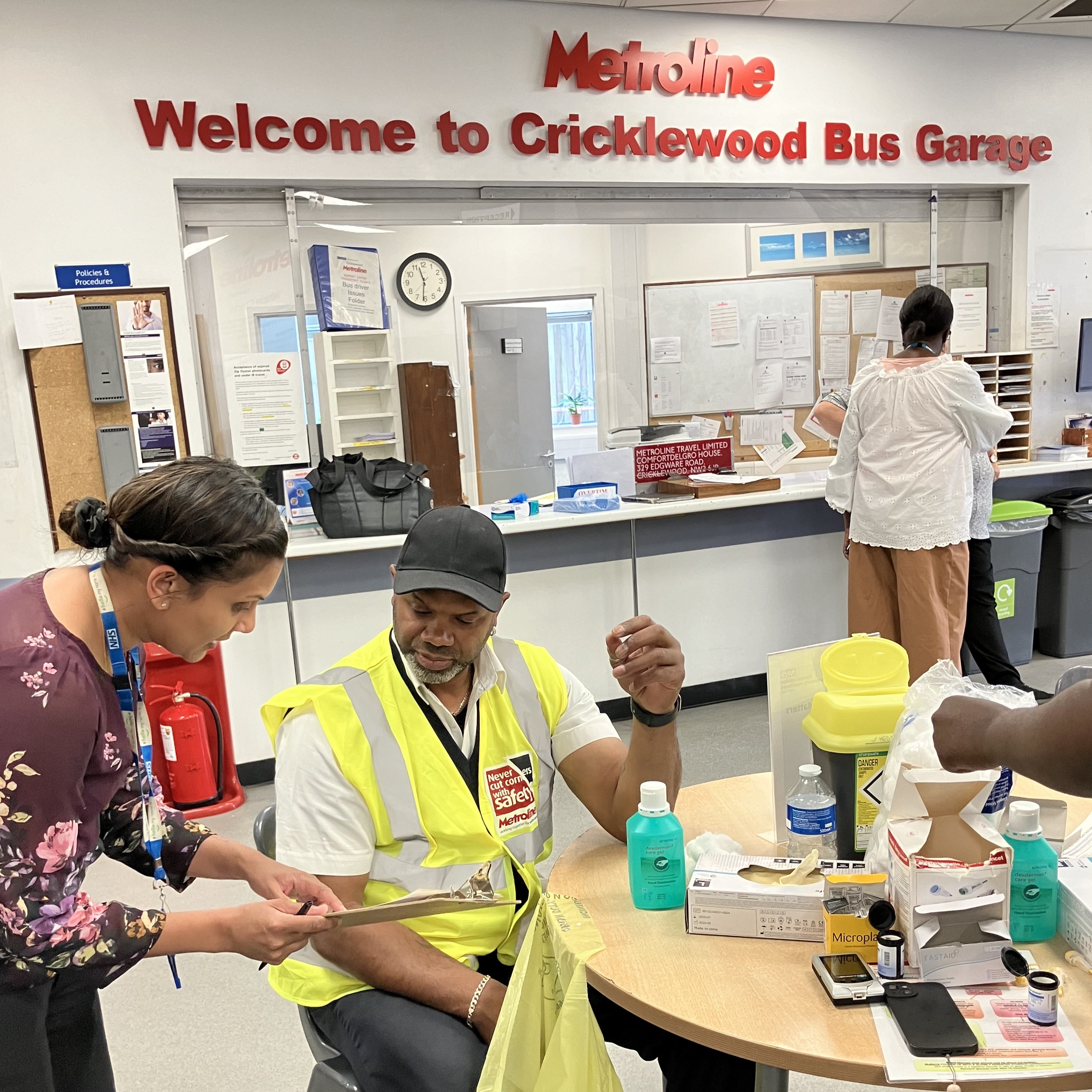 A woman giving a bus driver health advice at a bus depot