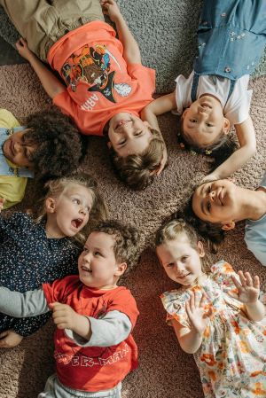 children lying in a circle looking up at camera