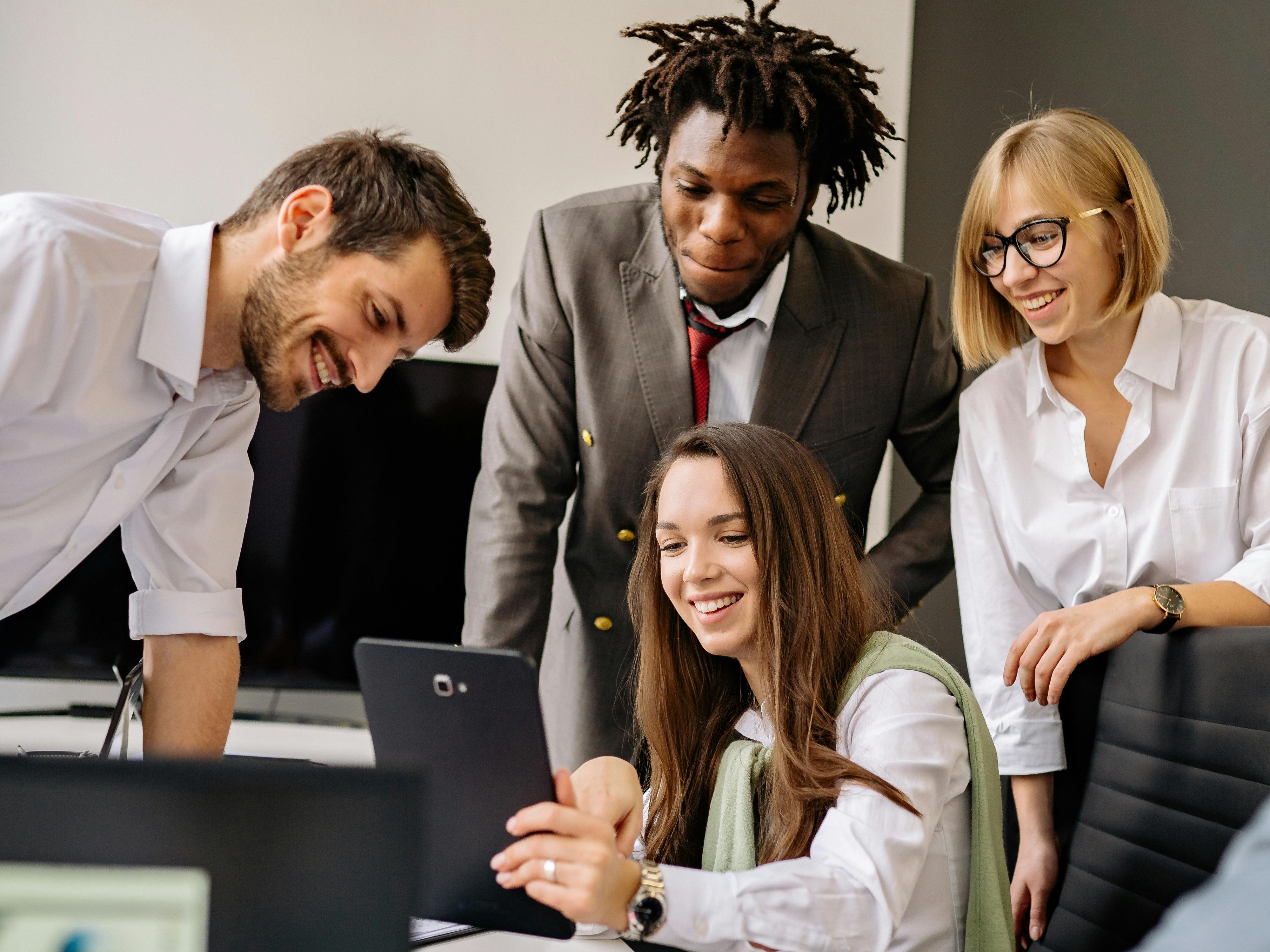 Mixed group chatting in office around laptop