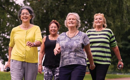 four women walking through park smiling