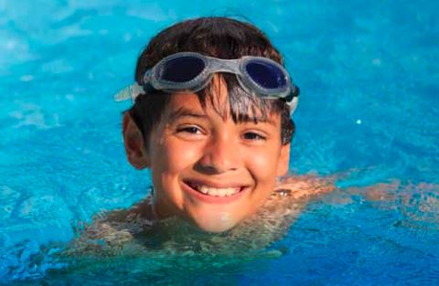 Young boy wearing goggles swimming in the water
