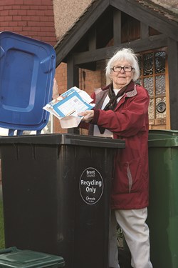 older lady placing cardboard in blue top bin 
