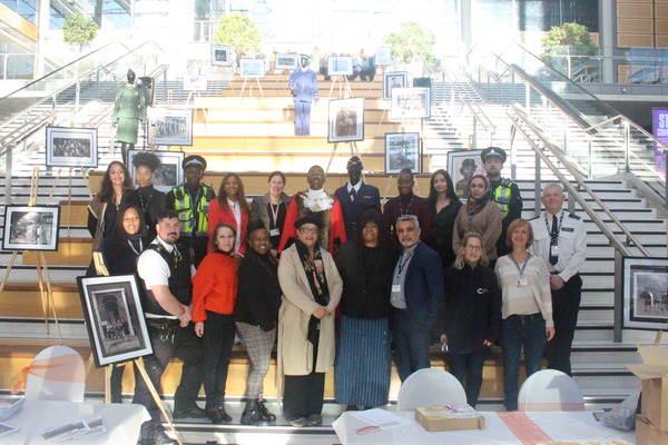 Group of people smiling together at the bottom of the stairs at Brent Civic Centre's atrium.