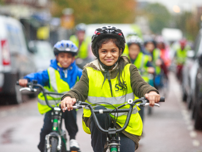 Photo of a young girl smiling whilst cycling her bike