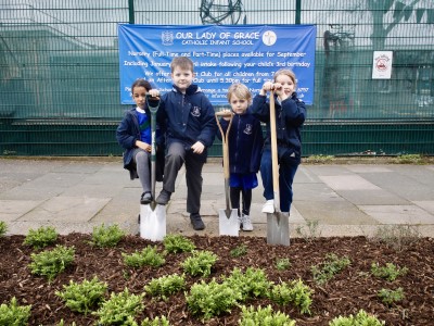 Pupils pose outside of school with shovels
